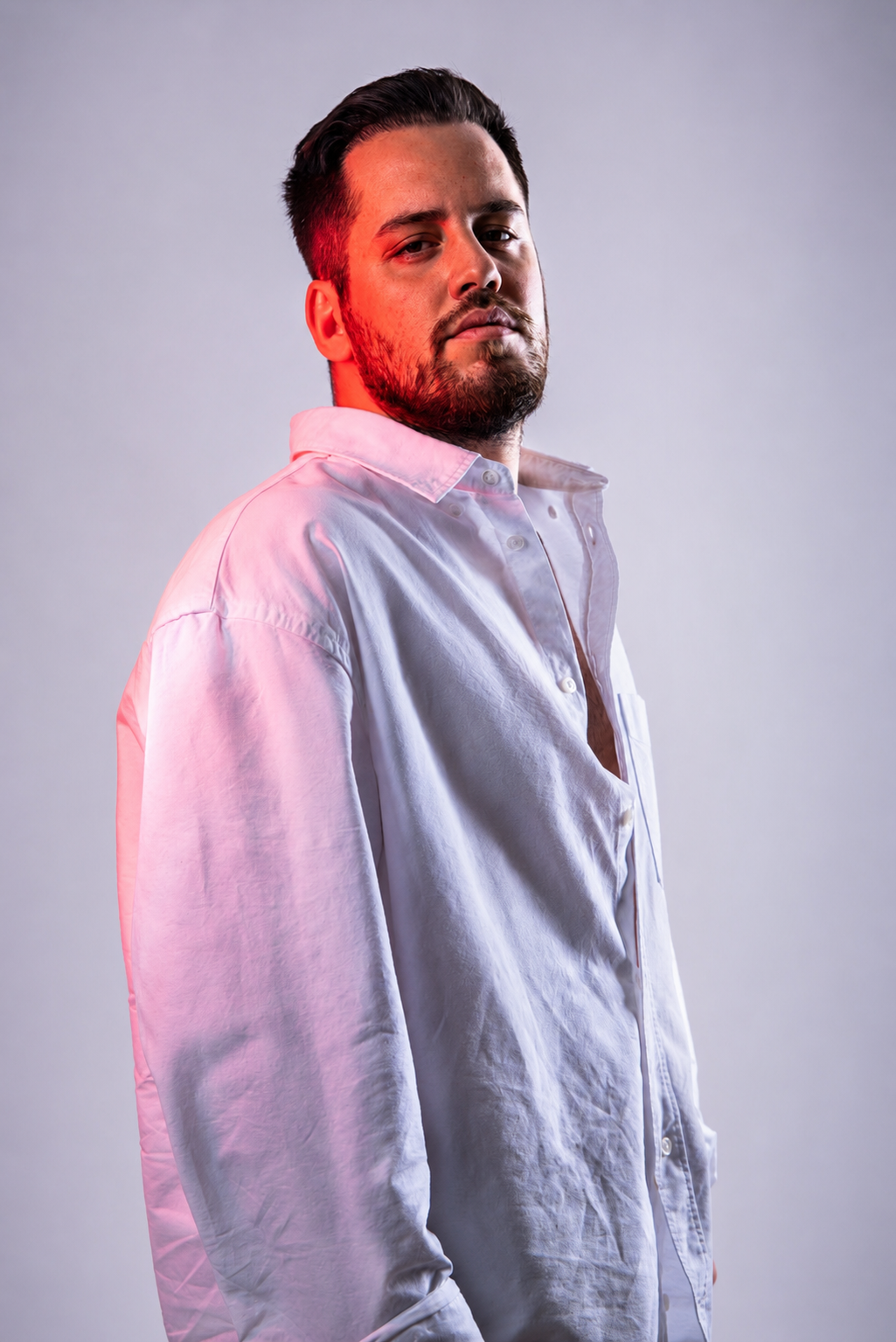 Studio portrait of Güven Akyol in a white shirt with red lighting