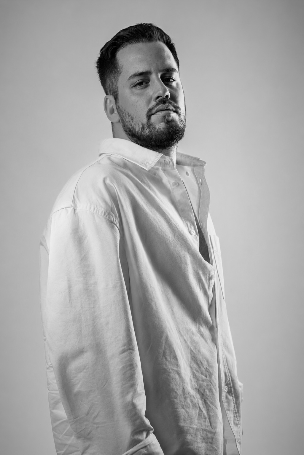 Black-and-white studio portrait of Güven Akyol
